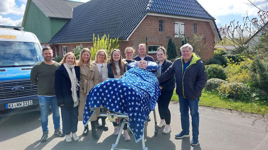 Eine Menschengruppe mit einer Frau auf einer Trageliege in der Mitte